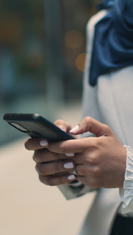 Vertikale-Video-Nahaufnahme-Einer-Muslimischen-Geschäftsfrau,-Die-Nachrichten-Auf-Dem-Mobiltelefon-überprüft,-Während-Sie-Vor-Dem-Büro-In-Der-Stadt-Steht